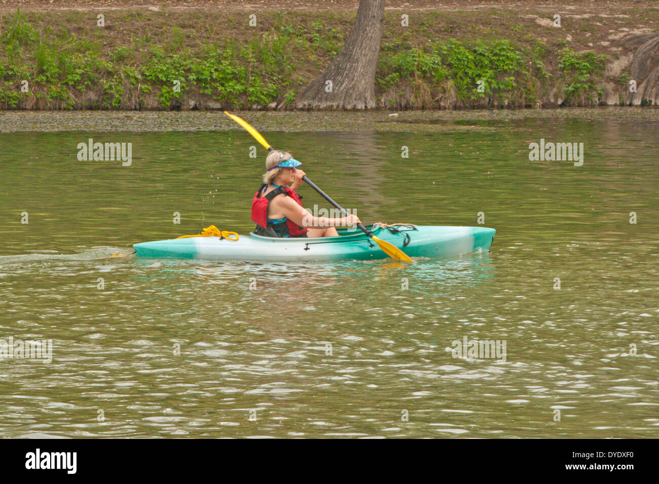 Woman wearing personal floatation device PFD paddling kayak in river Stock Photo