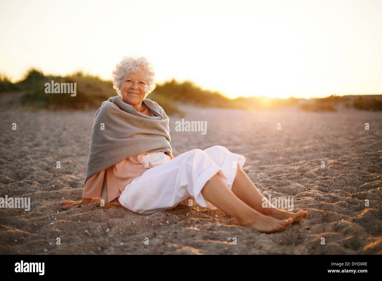 Relaxed Retired Woman Wearing Shawl Sitting On Sandy Beach Old Caucasian Woman Sitting On The