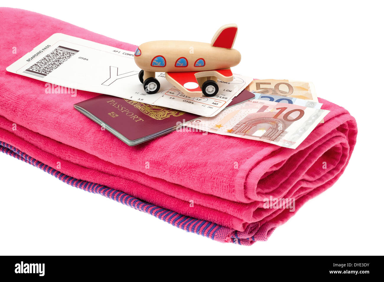 Holiday and travel concept image of a small aircraft placed onto a passport with money, an airline boarding card and towel. Stock Photo