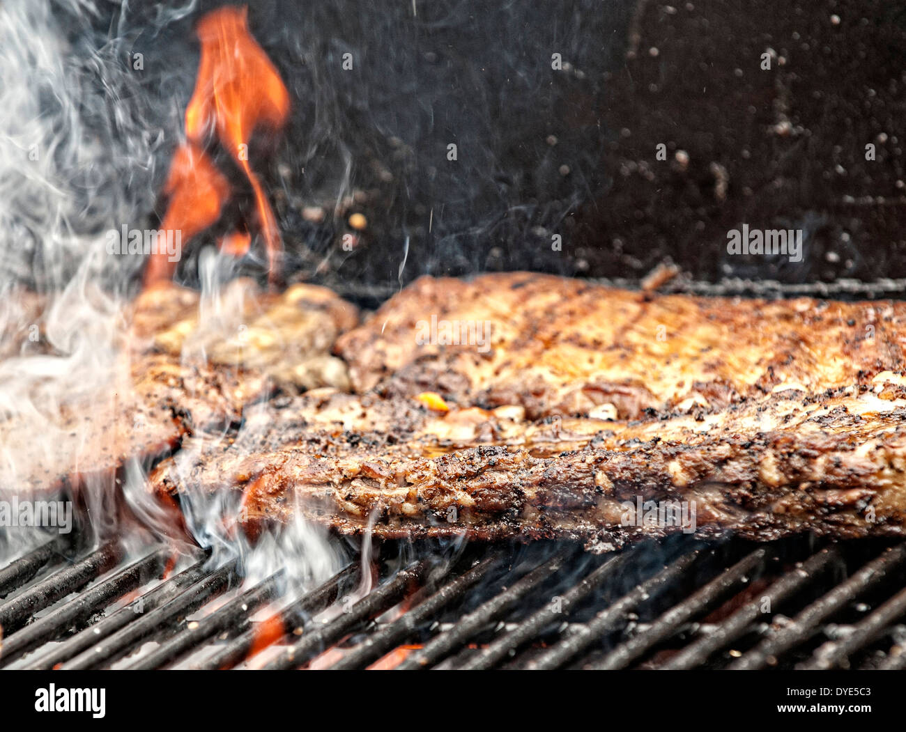 A slab of ribs can be seen slowly cooking over an open flame during the