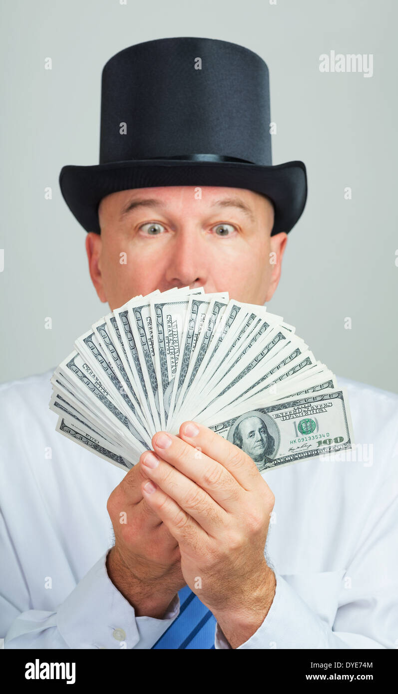 Surprised and amazed middle aged man in a retro top hat with money.Focus on the cash. Stock Photo