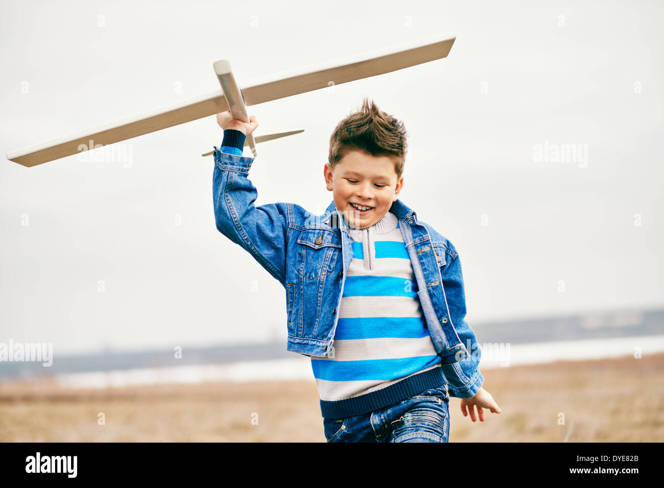 Photo of happy kid playing with toy airplane outside Stock Photo - Alamy
