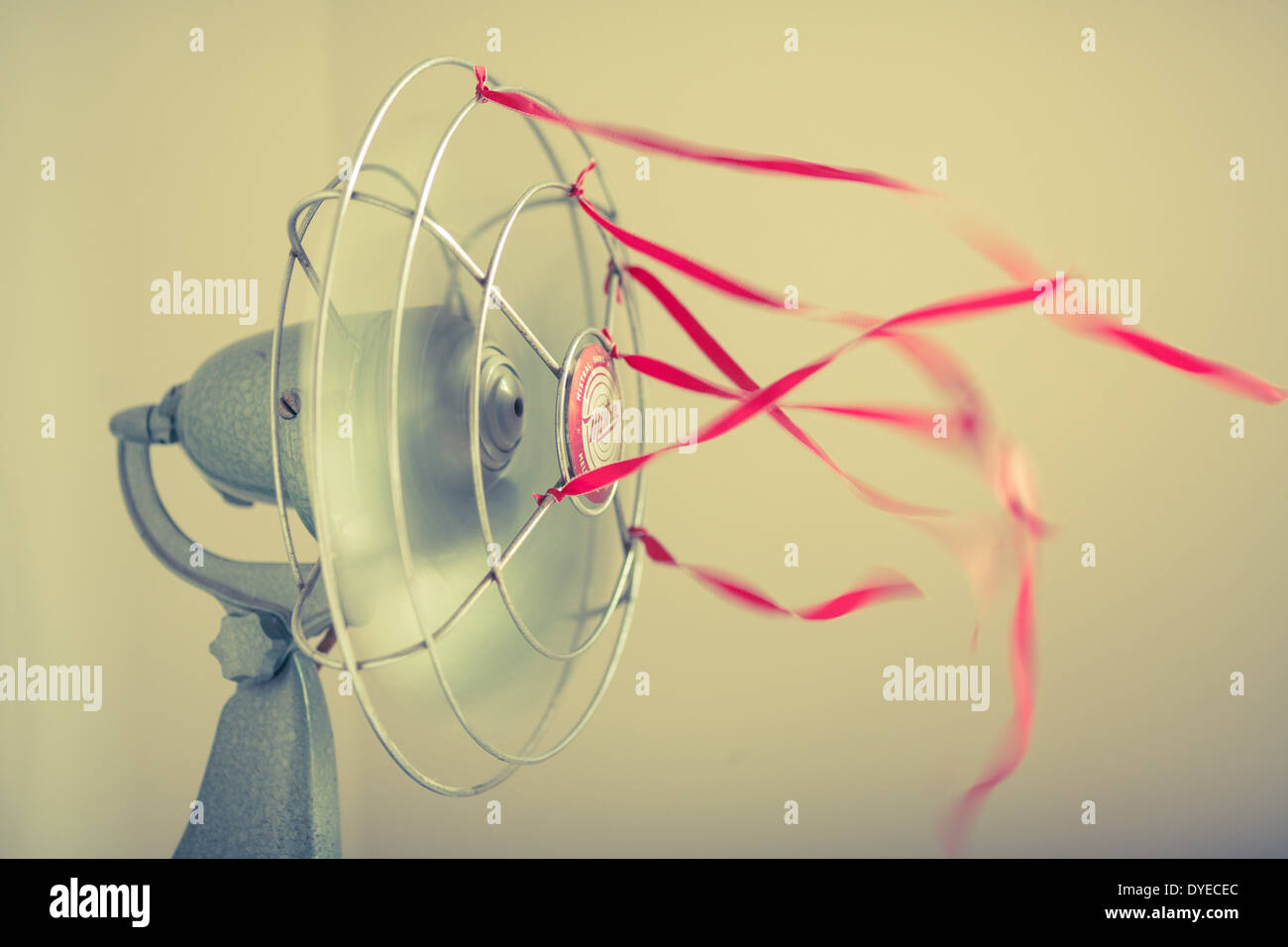 An old green desk fan with red ribbons against a white background Stock