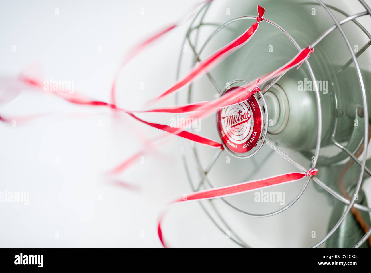 An old green desk fan with red ribbons against a white background Stock