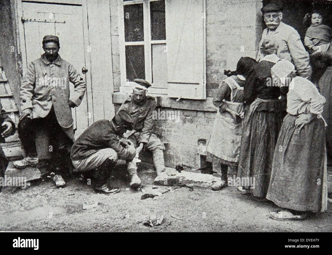 World War 1 - A major nursing a wounded German as villagers look with curiosity 1915 Stock Photo