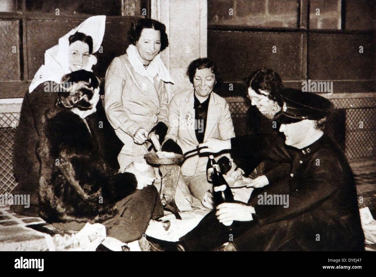 Group of women receive drinks from a Salvation Army man while cooking a meal on the streets of London waiting for the coronation of king George VI 1937 Stock Photo