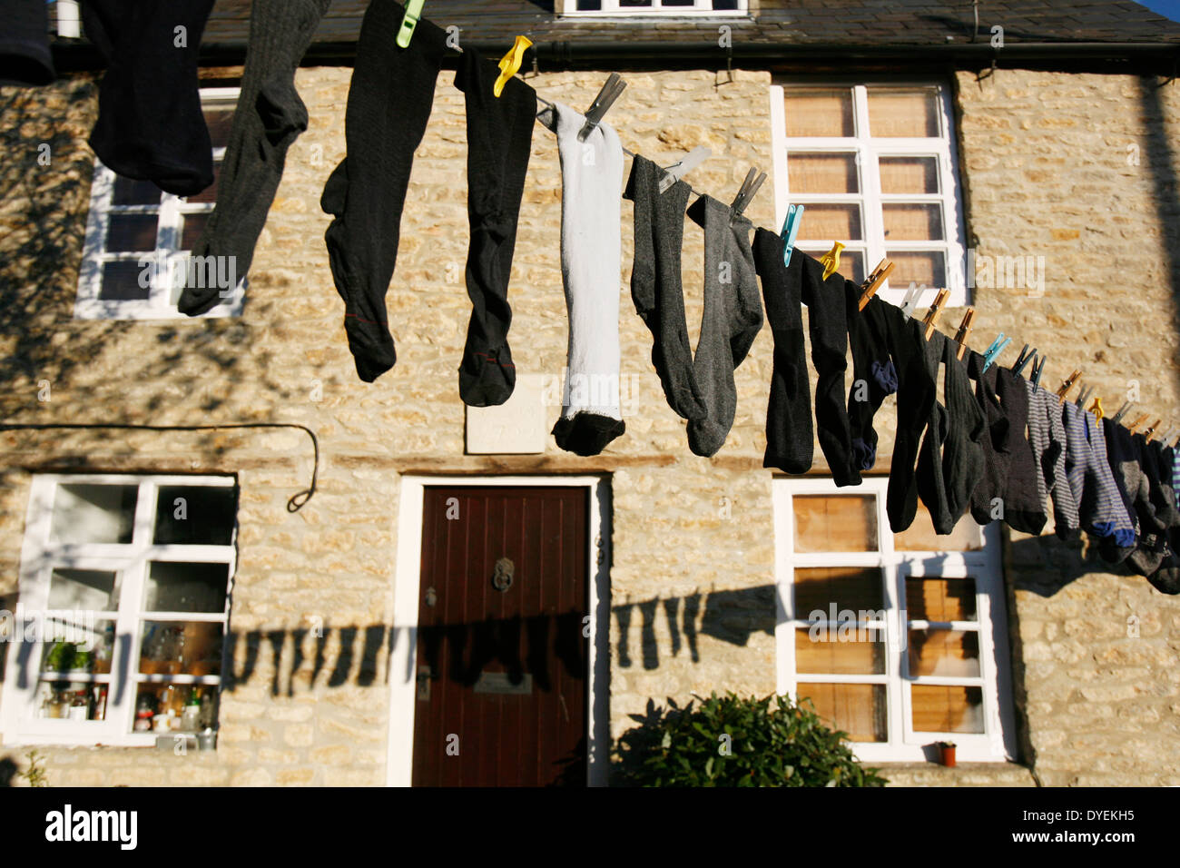 A mixture of different socks hanging and drying on a washing line outside. Stock Photo