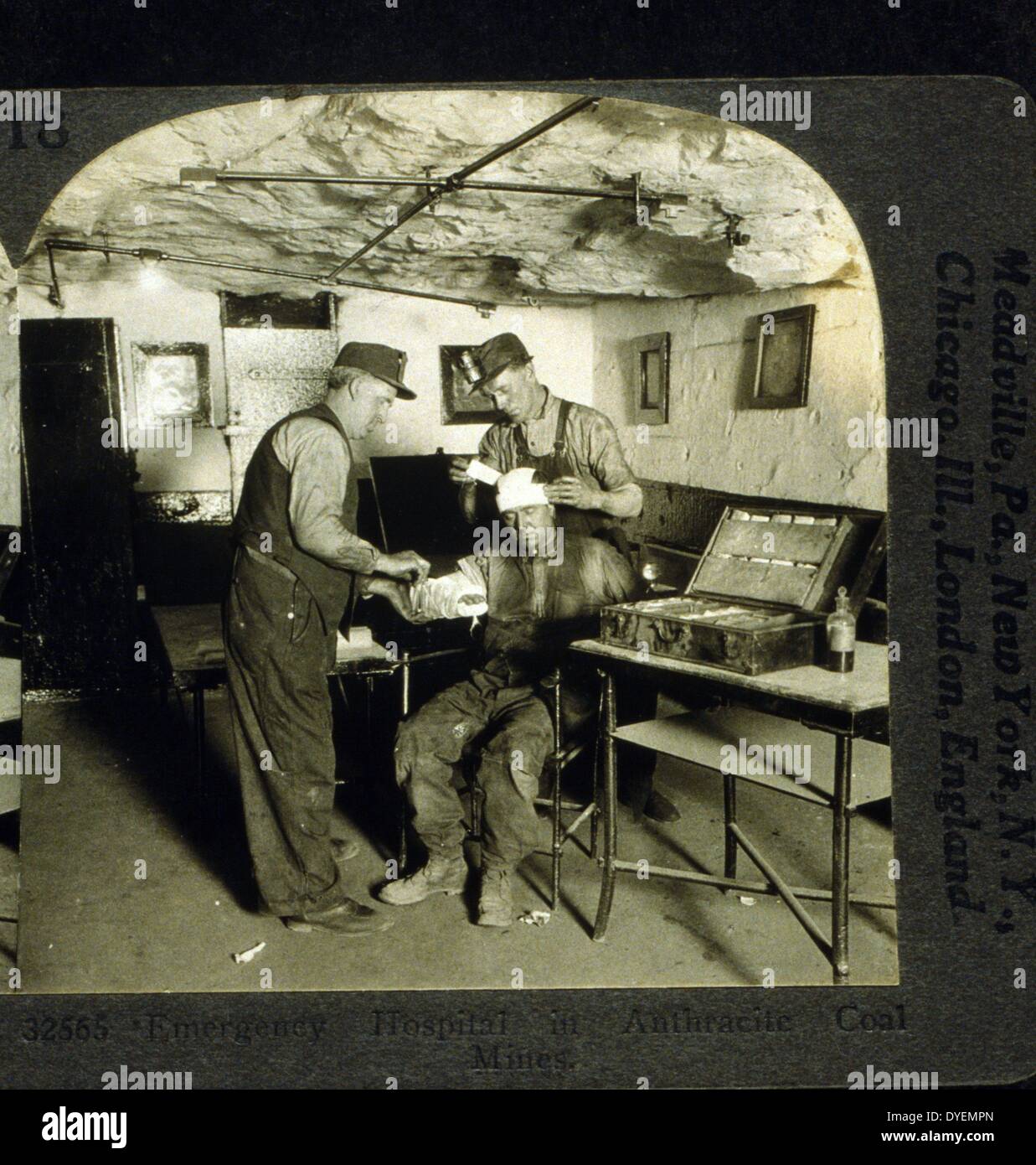 Emergency hospital in anthracite coal mines (between 1900 and 1920), photographic print on stereo card or stereograph. One man bandages head of injured man while another bandages his arm. Stock Photo