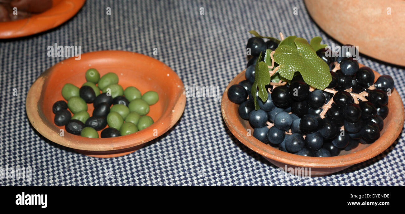 Models depicting typical Roman food from the early part of the Roman Empire. Grapes and olives are shown in simple clay dishes Stock Photo