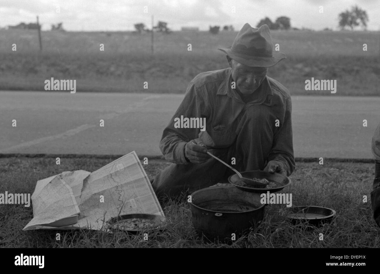 Migrant agricultural worker dishing up the noonday lunch of blackberry pie while camped by the roadside east of Fort Gibson, Muskogee County, Oklahoma By Russell Lee, 1903-1986, photographer Date 19390101 Stock Photo