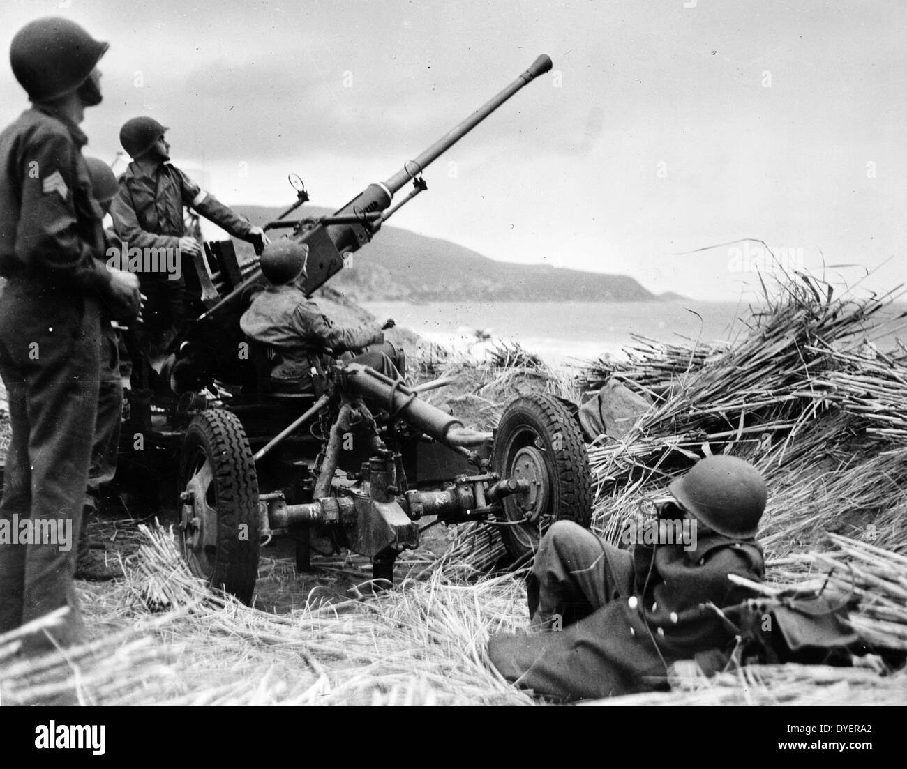 Anti-aircraft bofors gun in at position on a mound overlooking the beach in Algeria, with a United States anti-aircraft artillery crew in position 19430101. Stock Photo
