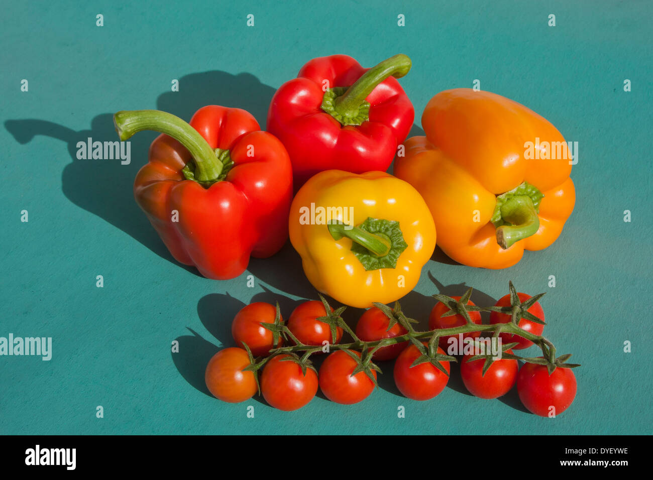 Cherry Tomatoes and Bell Peppers on green background Stock Photo