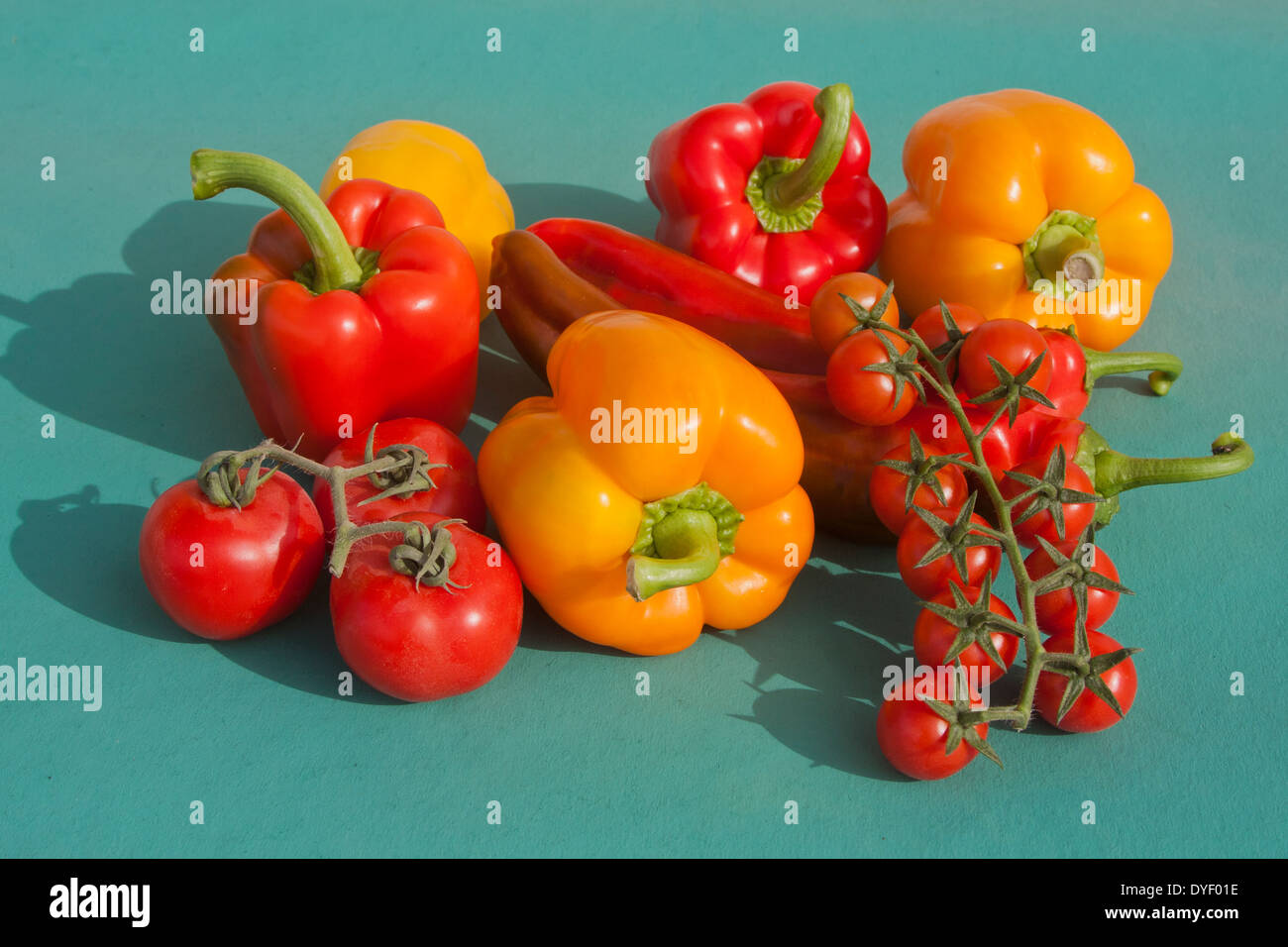 Cherry Tomatoes Chilli and Bell Peppers on green background Stock Photo