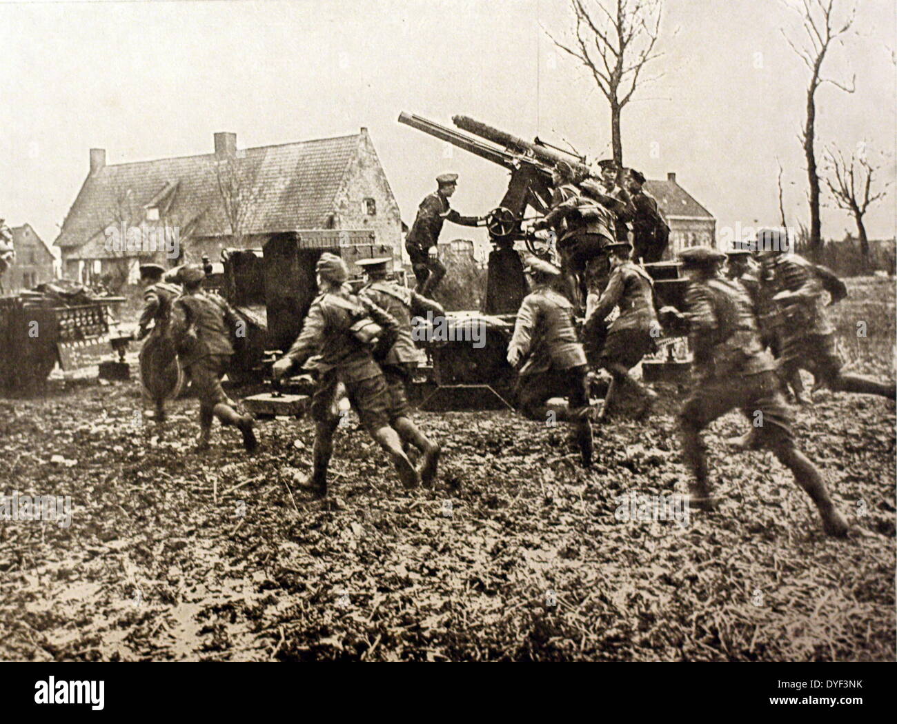 A photograph from the First World War, showing soldiers running into an area while two gunners man an anti aircraft gun just next to them. Circa 1914-1918. Stock Photo