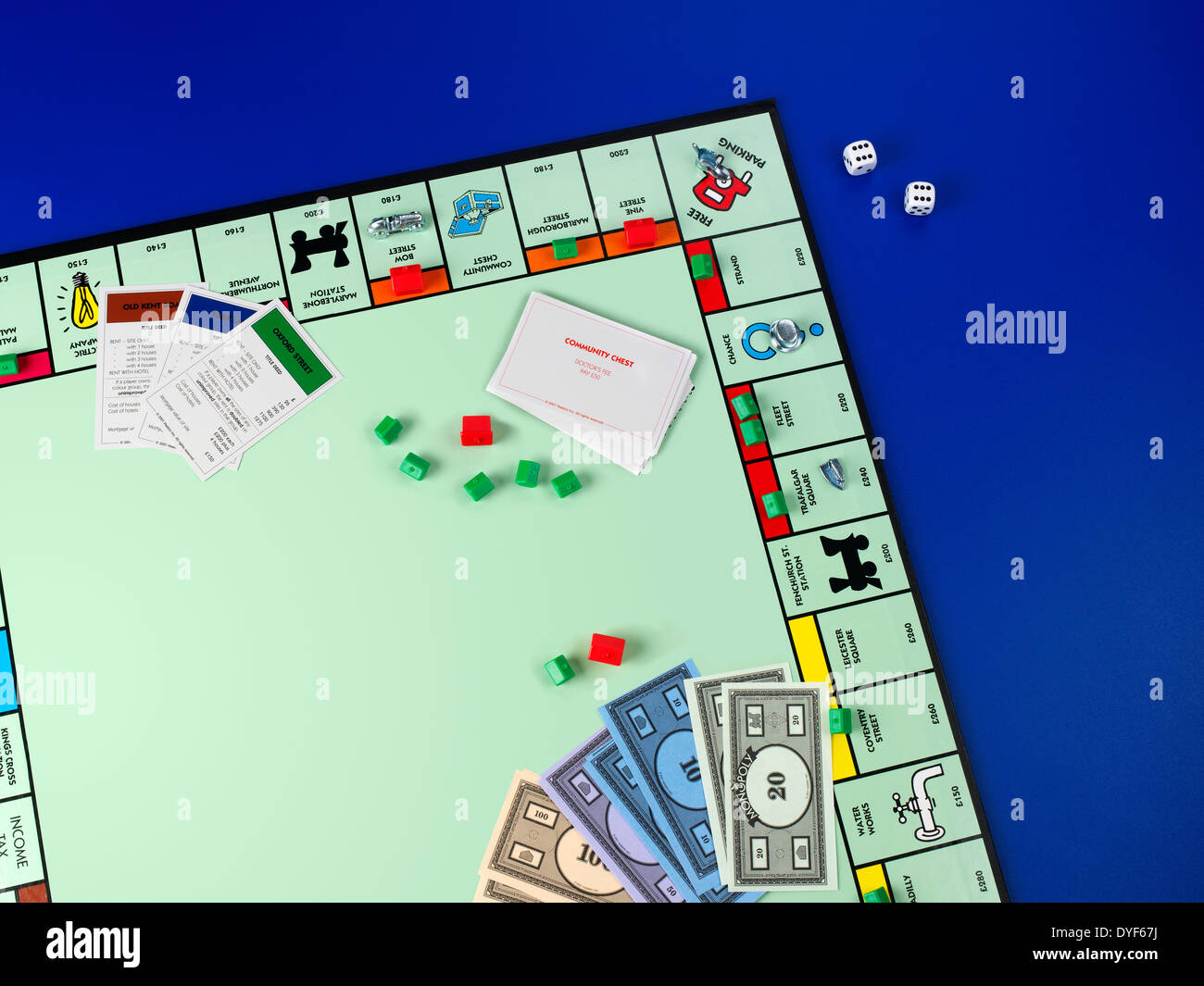 AN ARIEL SHOT OF PART OF A MONOPOLY BOARD WITH MONEY AND DICE AND HOUSES ETC ON A BLUE BACKGROUND Stock Photo