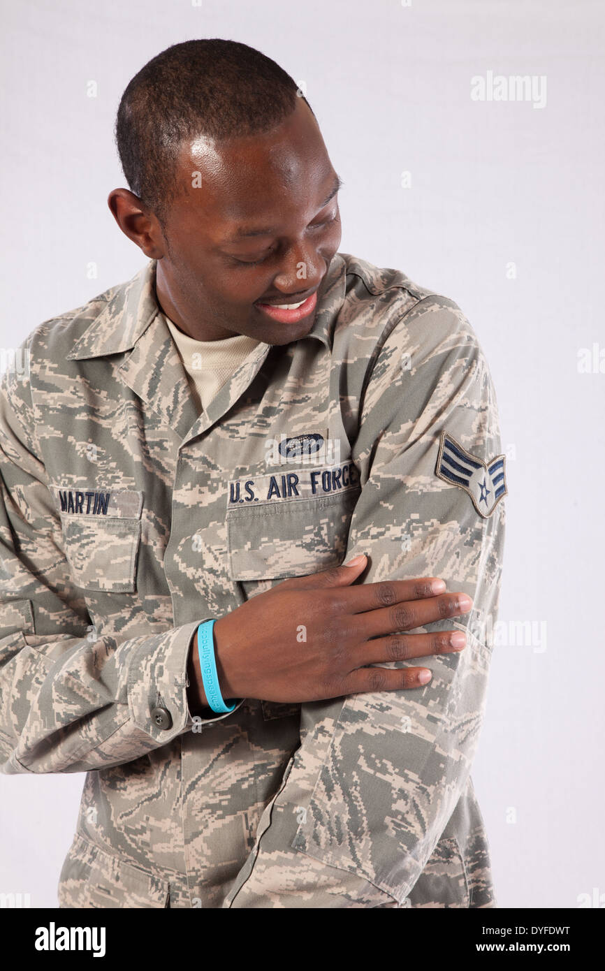 Black man in U.S. Air Force camouflage,fatigues, standing and looking at his sleeve  with a  smile Stock Photo