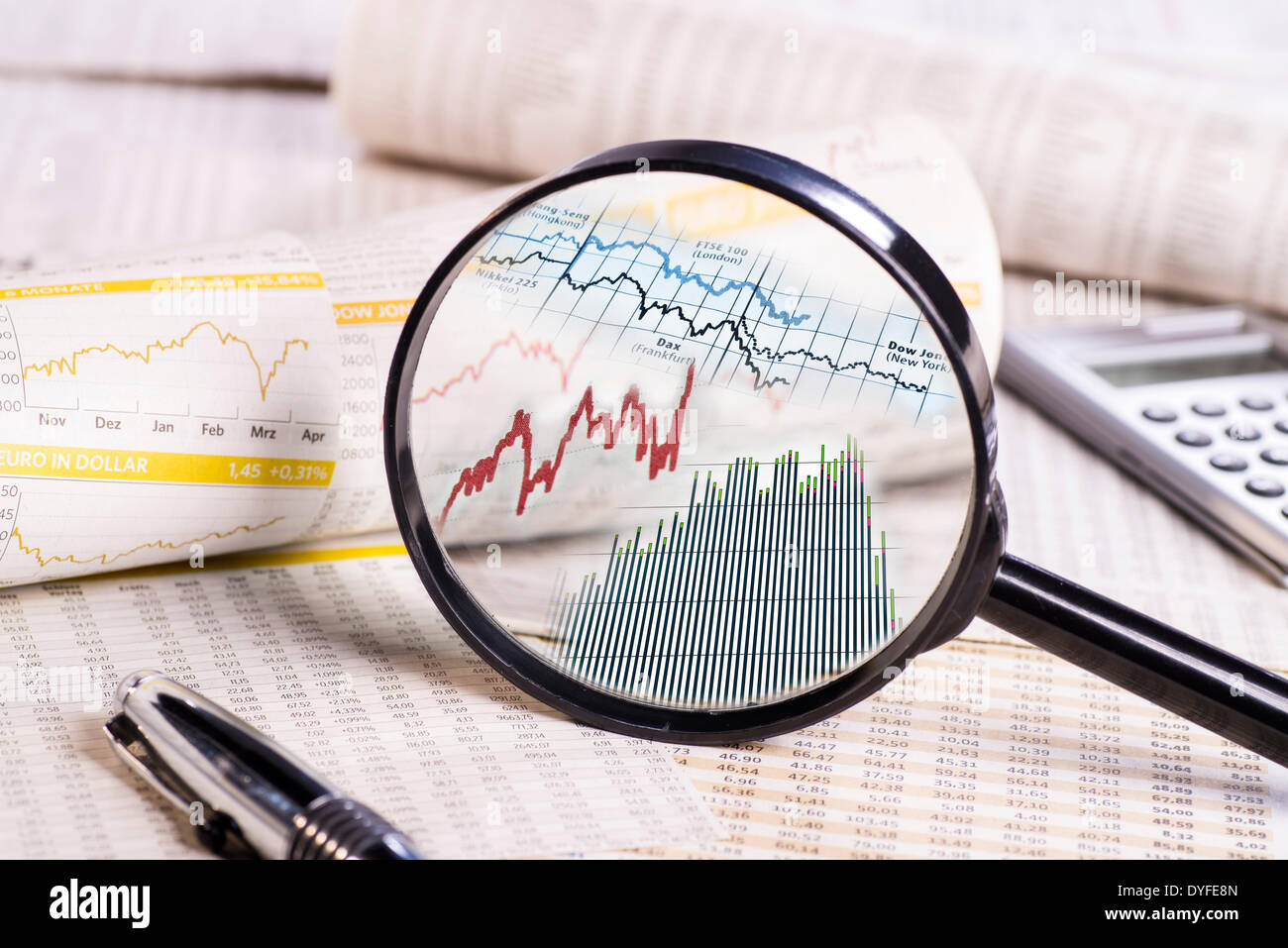 Magnifier with stock prices on papers with rate charts. Digital Image Editing [M] - April 2014 Stock Photo