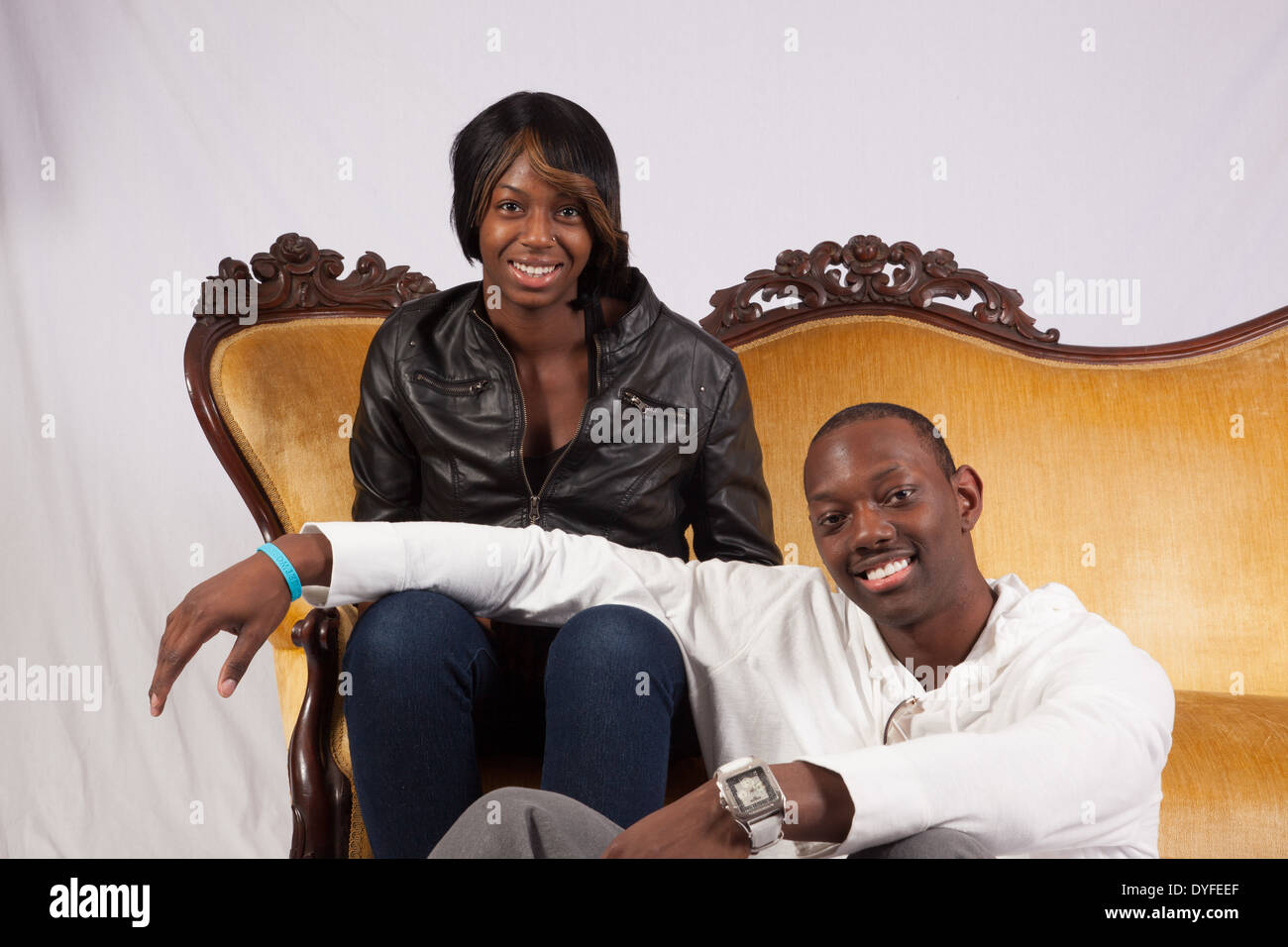 Black man and woman sitting together in a romantic mood, looking at the camera with a smile Stock Photo