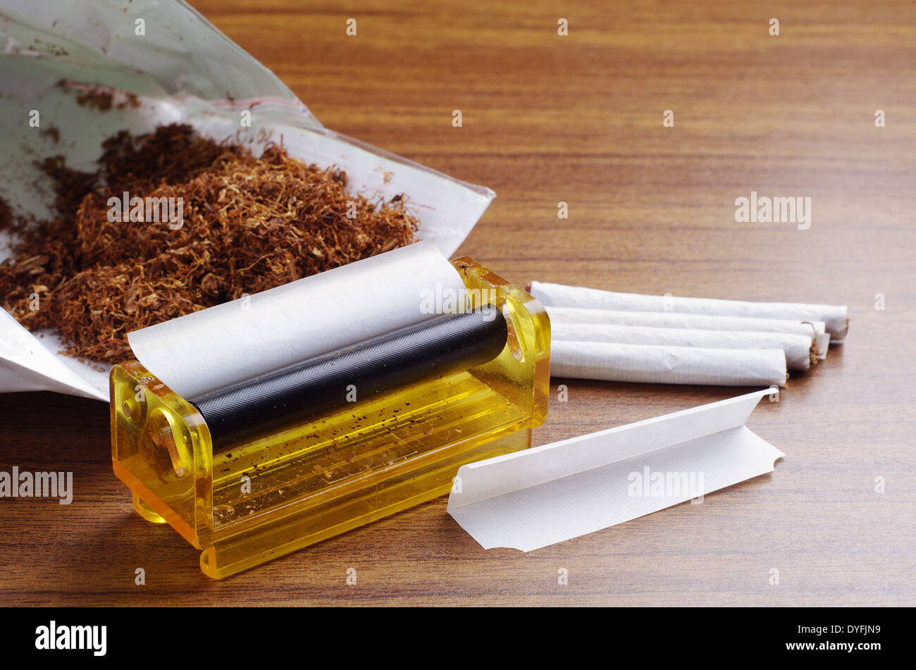 Tobacco and rolling machine on brown table Stock Photo