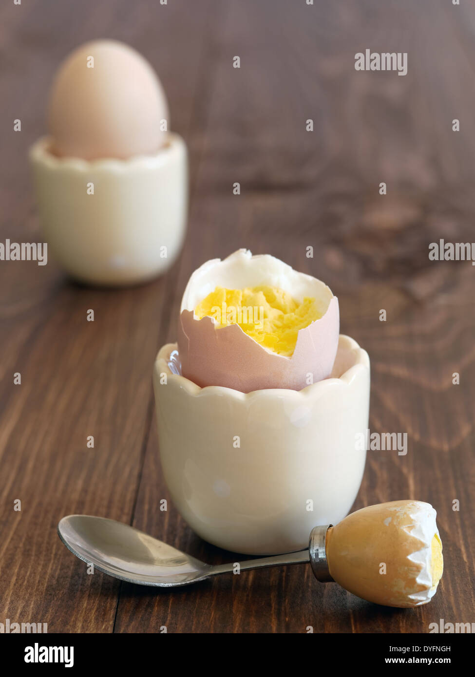 Boiled eggs in cups with a funny egg spoon Stock Photo