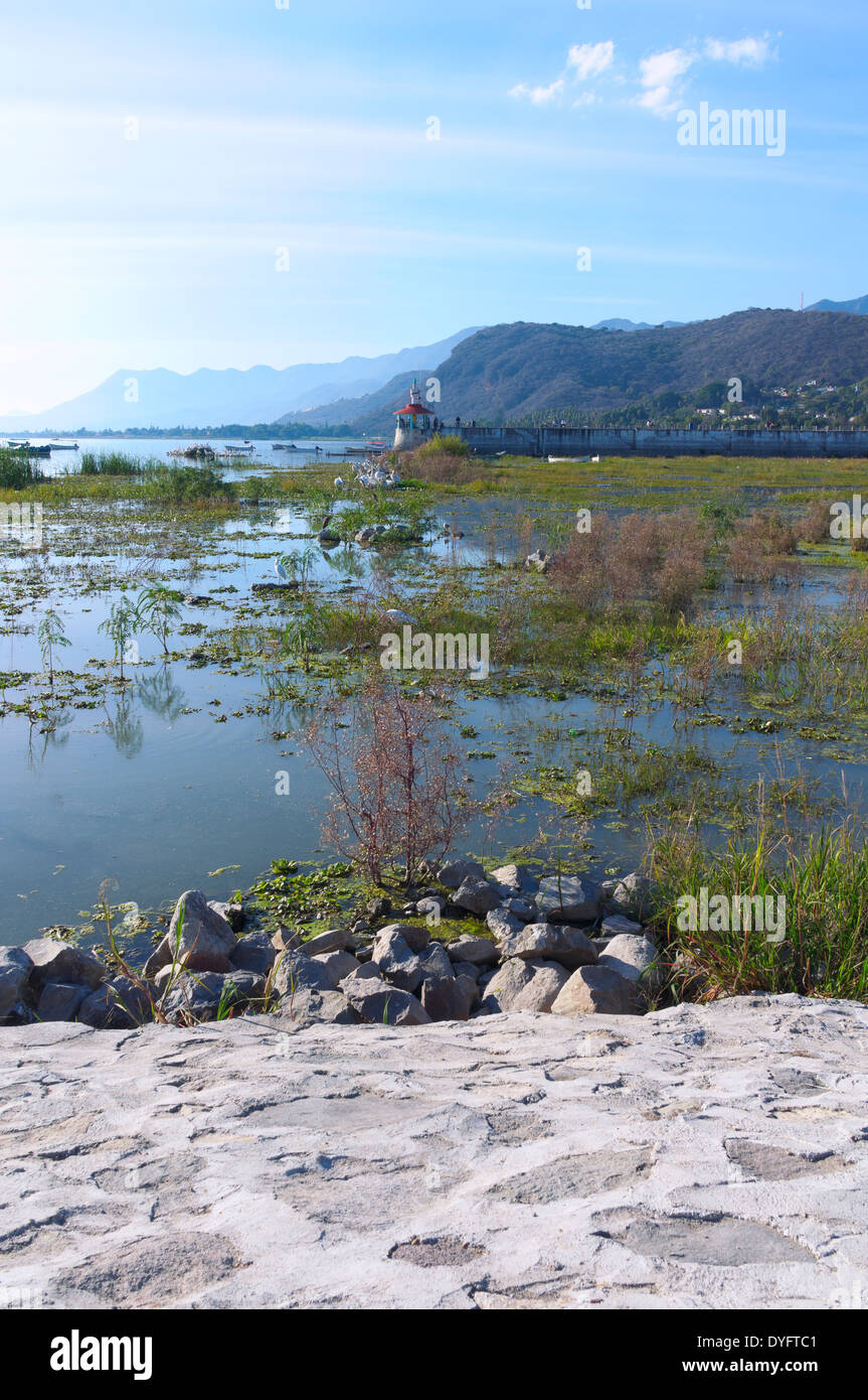 Lake Chapala inlet with boats birds pier and surrounding mountains in