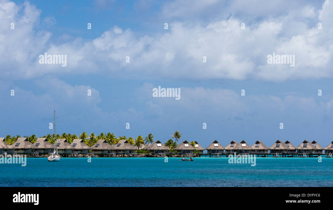 Row of overwater bungalows with sailboat and rowboat in Bora Bora, French Polynesia Stock Photo
