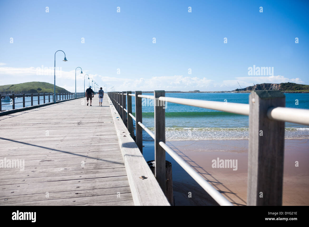 Two people walk out along the Long pier  at Coff's Harbour, Australia two people in March 2014. Stock Photo