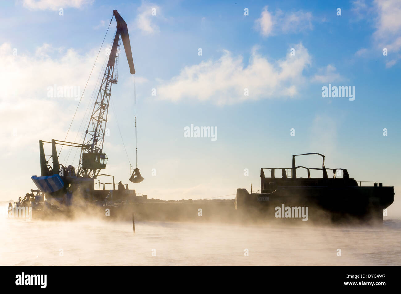 Floating crane barge unloads sand, gravel Stock Photo