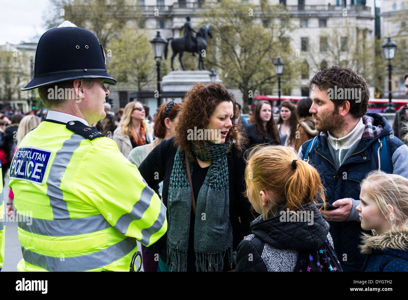 A Metropolitan Police Officer assisting a family of tourists in Trafalgar Sqaure. Stock Photo