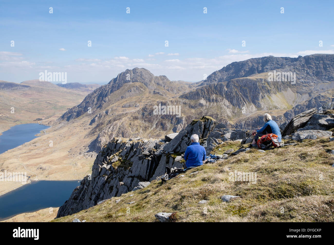 Hikers resting on Y Garn mountain with view to Mount Tryfan and Glyderau in mountains of Snowdonia National Park, Ogwen, North Wales, UK Stock Photo