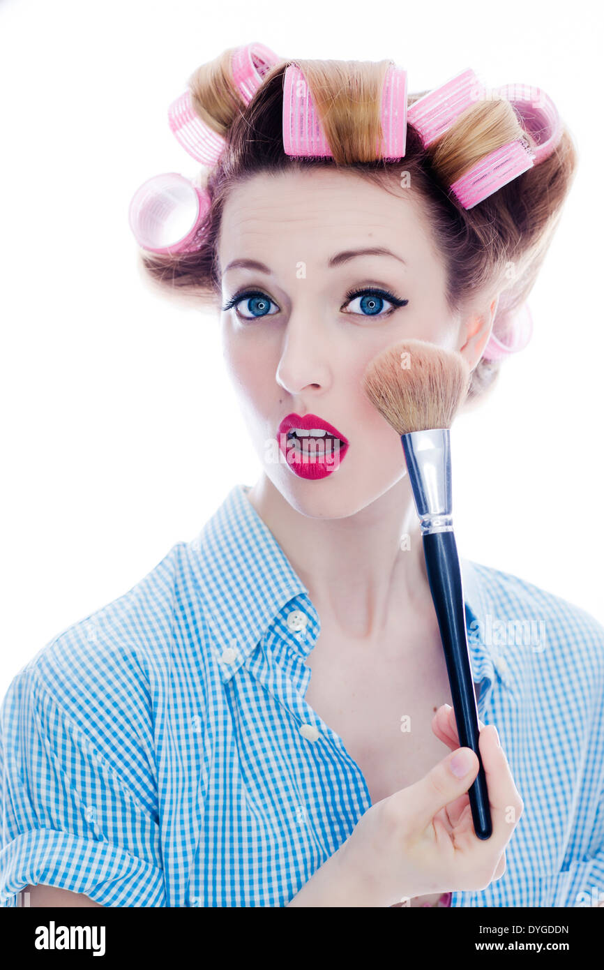 Junge Frau mit Puderpinsel und Lockenwicklern im Haar - woman with make-up brush and hair roller Stock Photo