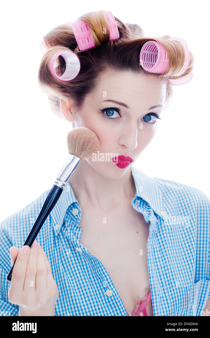 Junge Frau mit Puderpinsel und Lockenwicklern im Haar - woman with make-up brush and hair roller Stock Photo