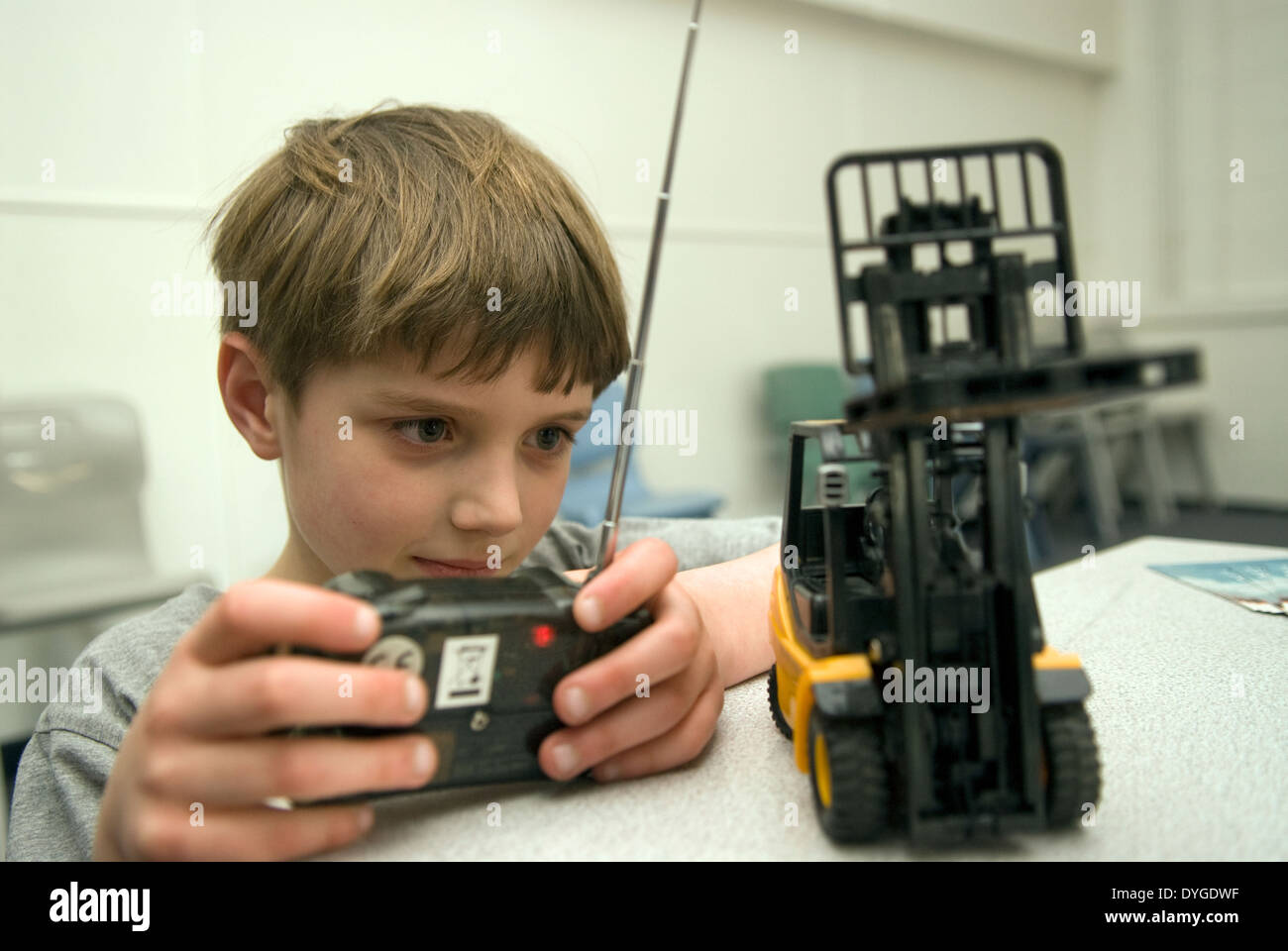 7 year old boy learning about truck mechanics with a remote control forklift truck, Liphook, Hants, UK. Stock Photo