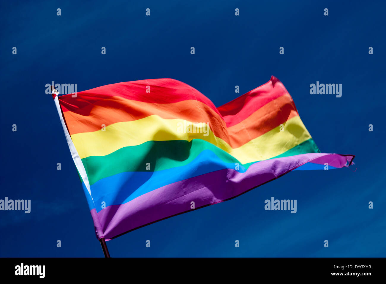 Rainbow flag against blue sky Stock Photo