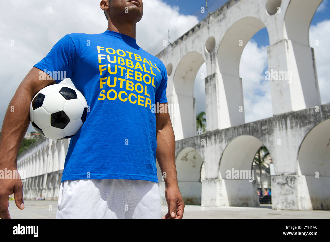 Brazilian soccer player wearing international football shirt holding soccer ball at Lapa Arches in Rio de Janeiro Stock Photo