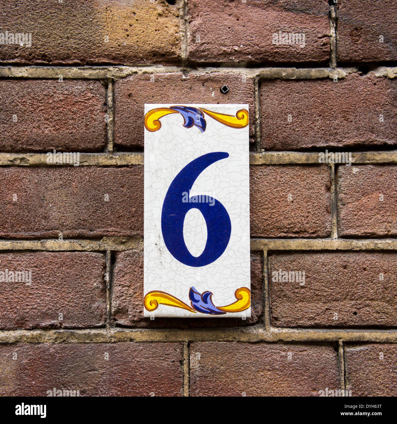 House number six on ceramic tile. Blue lettering on a white background. Stock Photo