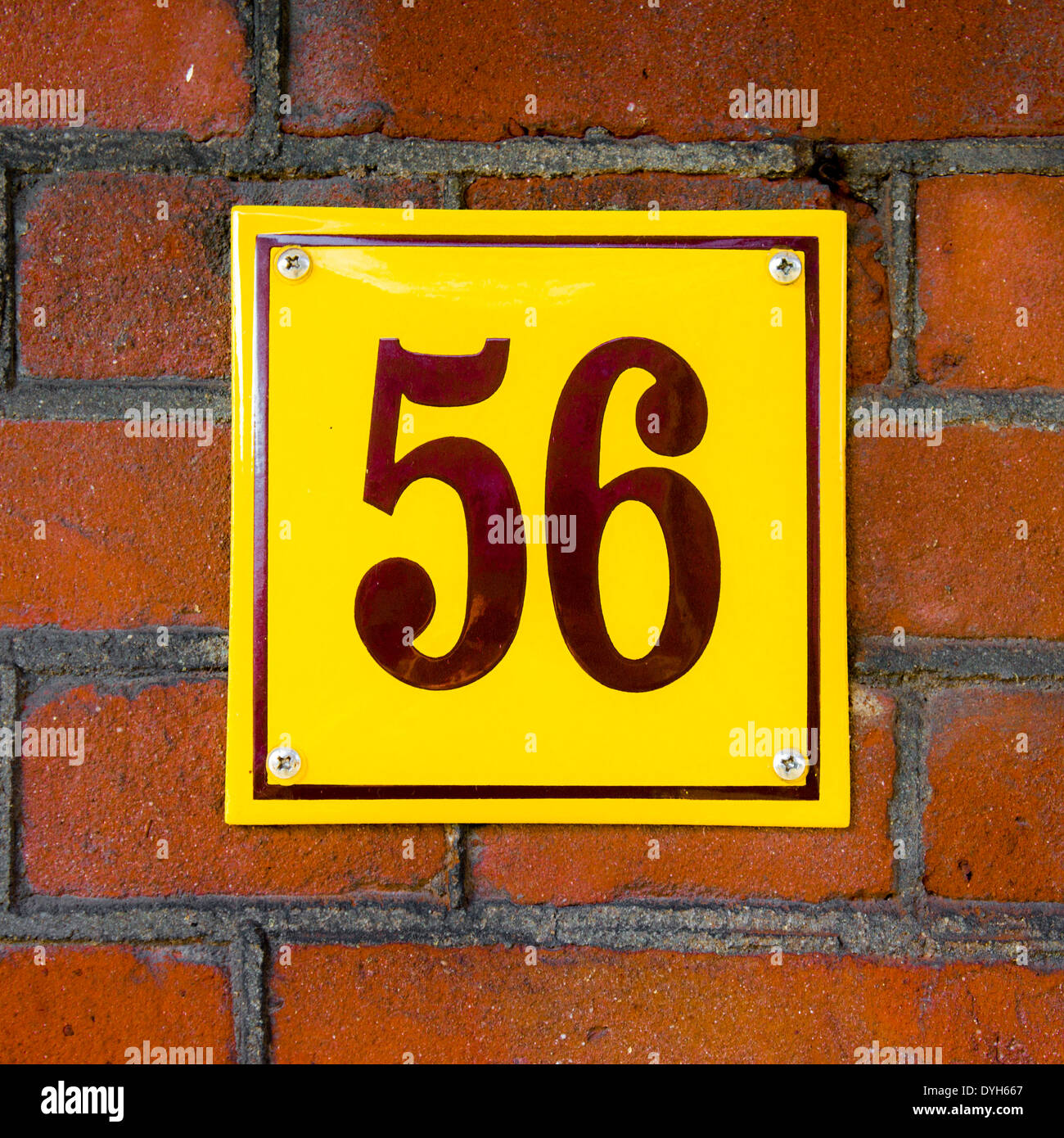 Enameled house number fifty six. Brown lettering on a yellow background. Stock Photo