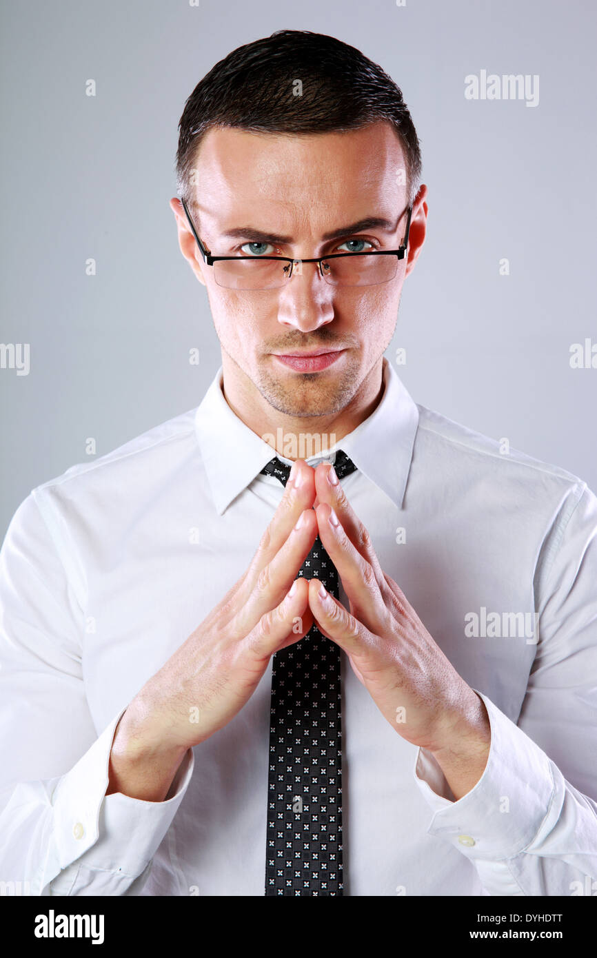 Confident businessman folding his hands together on gray background