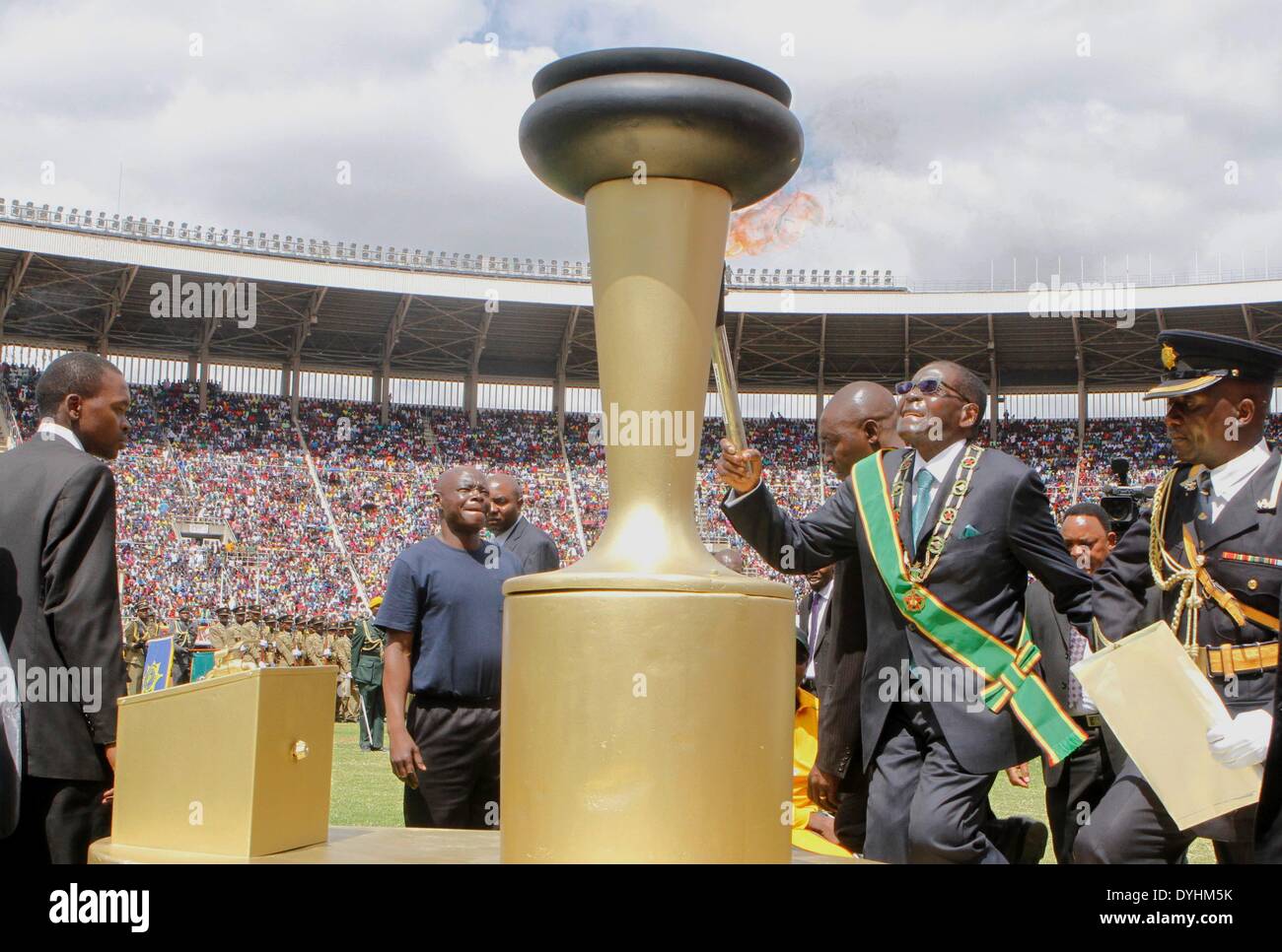 Harare, Zimbabwe. 18th Apr, 2014. Zimbabwean President Robert Mugabe (2nd R) walks to light a giant torch at a grand ceremony held at the National Sports Stadium, in the west suburbs of Harare, Zimbabwe, April 18, 2014. Zimbabwe celebrated the 34th year of independence from Britain on Friday. Tens of thousands of Zimbabweans attended the annual ceremony. Credit:  Stringer/Xinhua/Alamy Live News Stock Photo