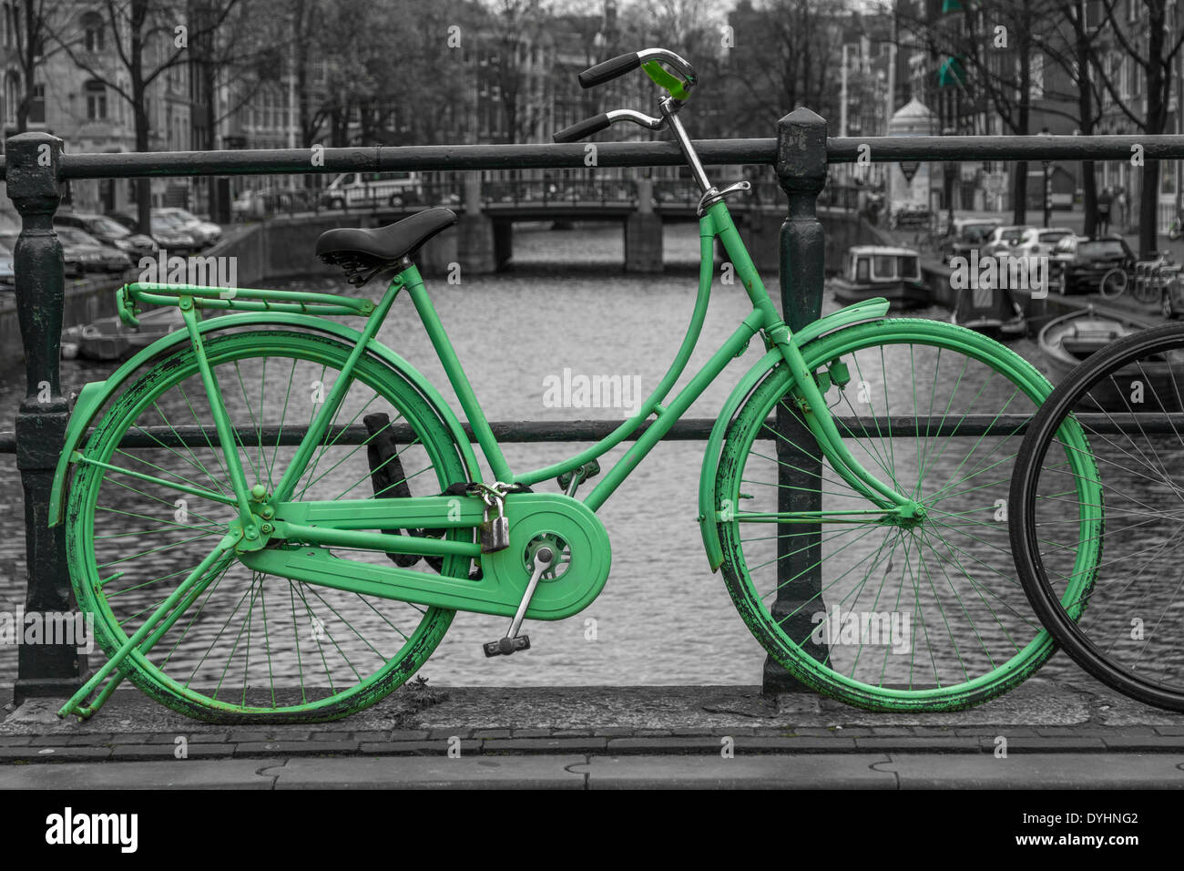 Green bike isolated on black and white city background of canals in Amsterdam, Holland Stock Photo