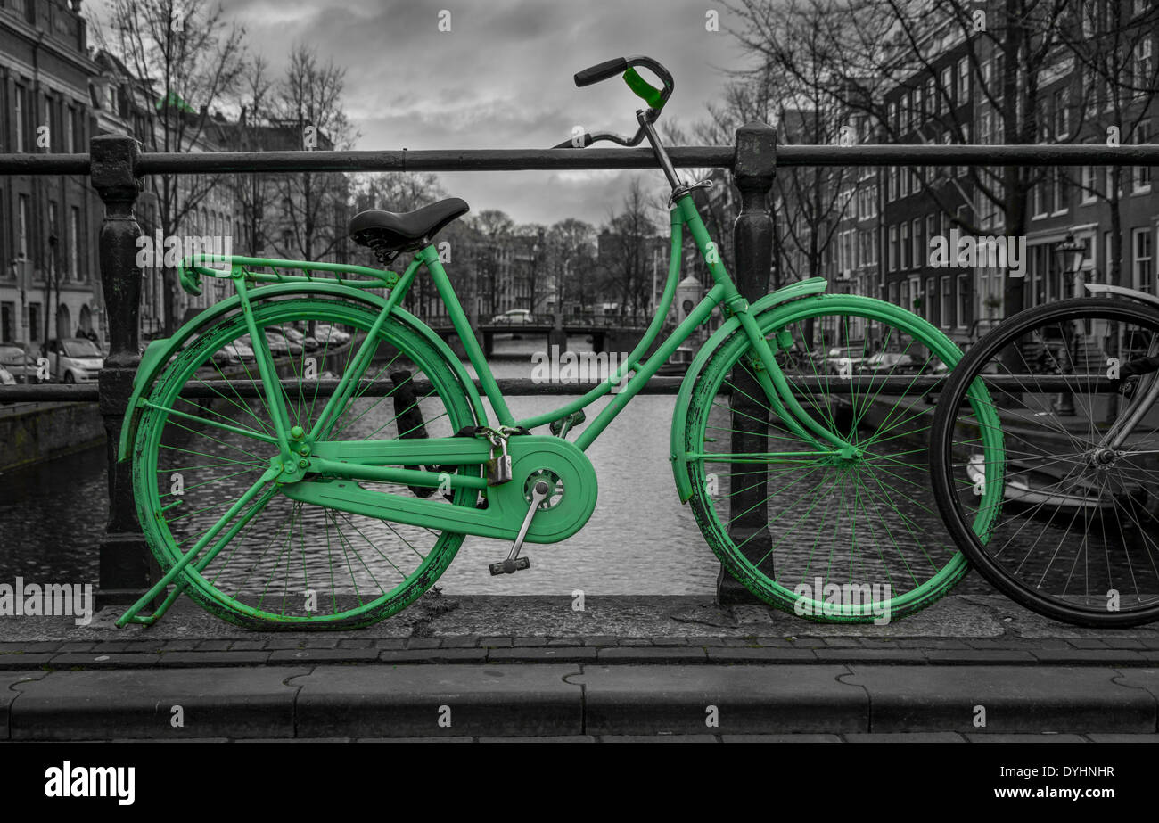 Green bike isolated on black and white city background of canals in Amsterdam, Holland Stock Photo