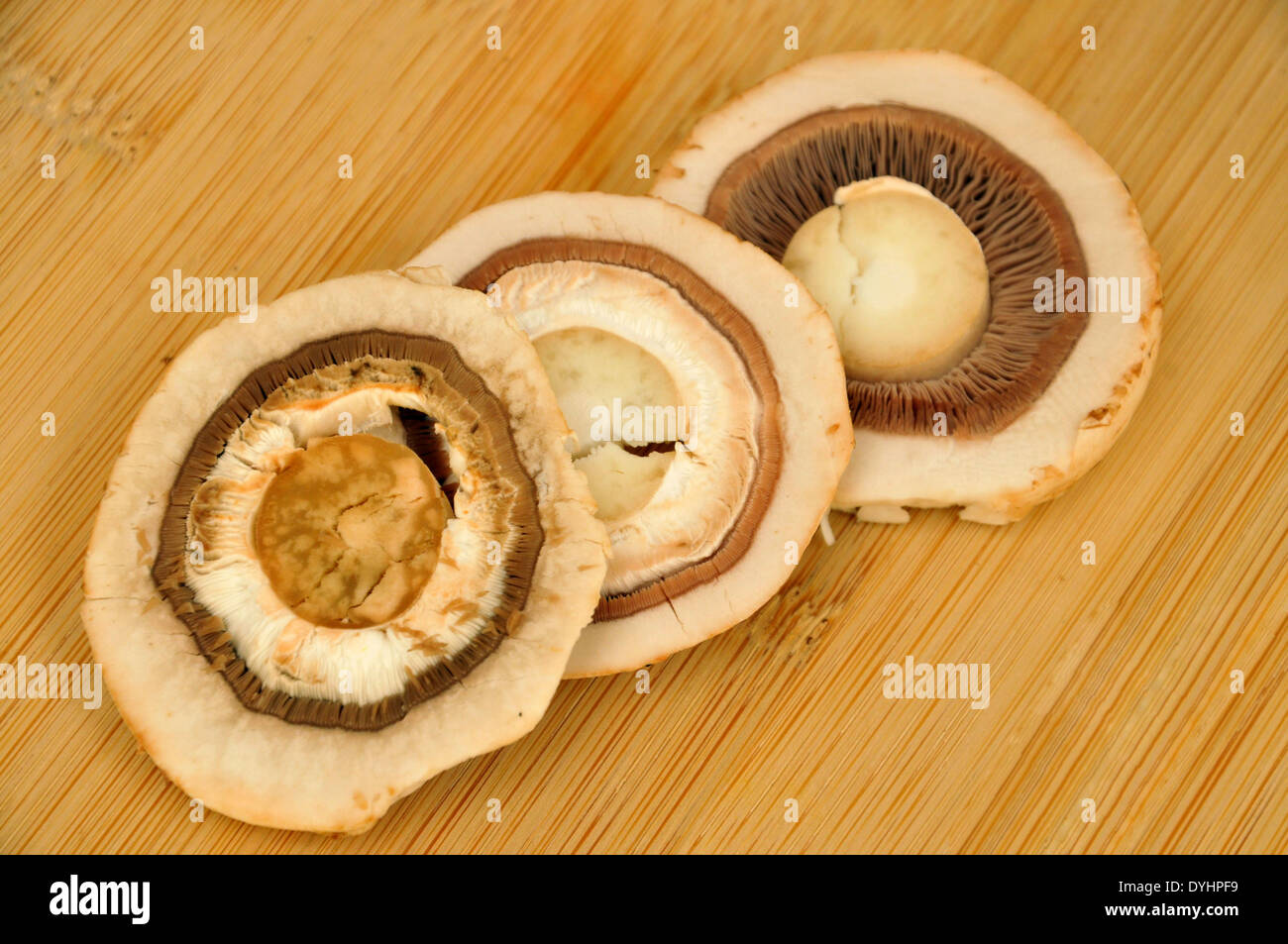 Fresh Button Mushrooms Sliced Three Ways on Wooden Board Stock Photo