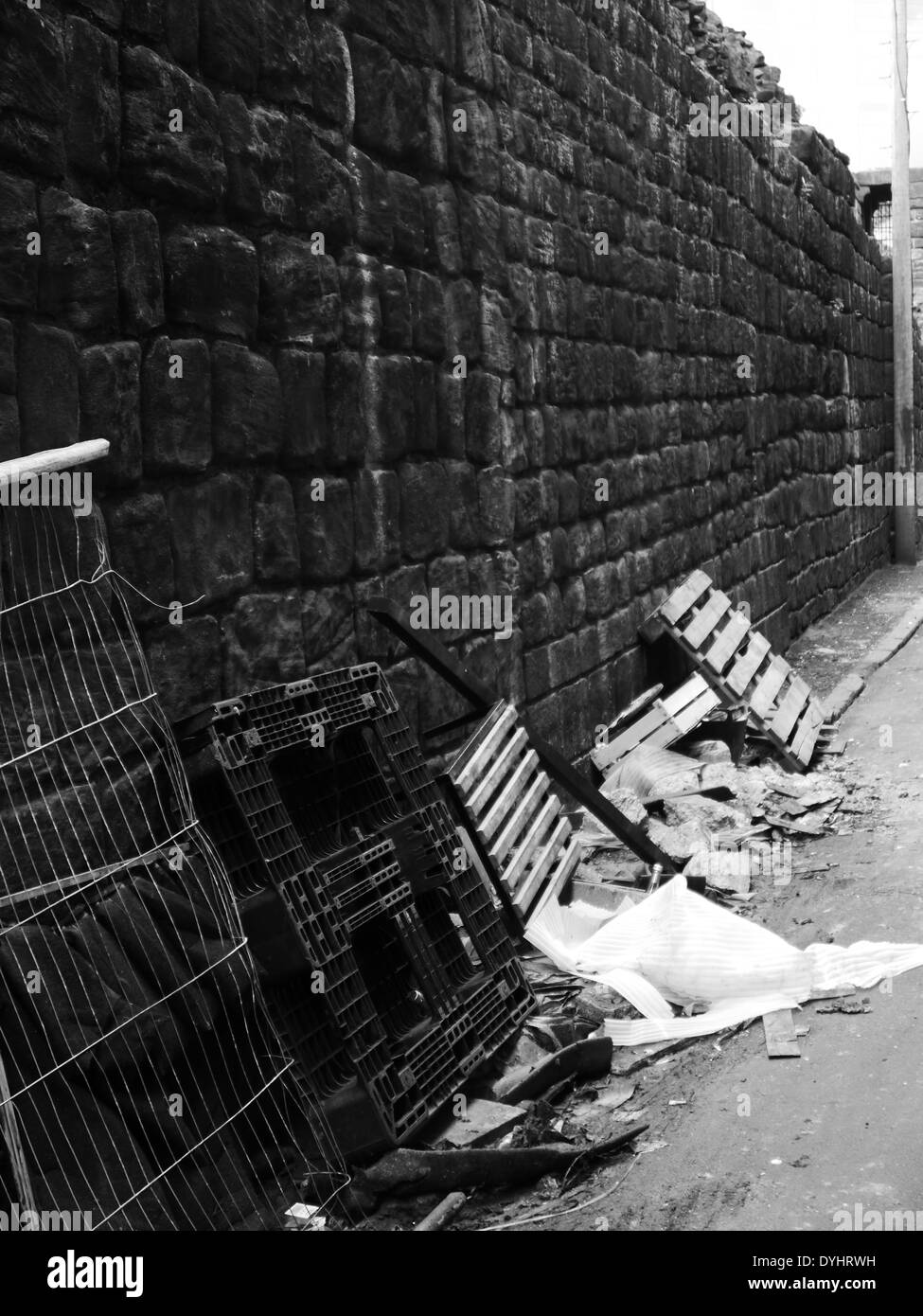 Monochrome image - Urban street scene showing refuse / debris next to historic City wall, Newcastle upon Tyne, England, UK Stock Photo