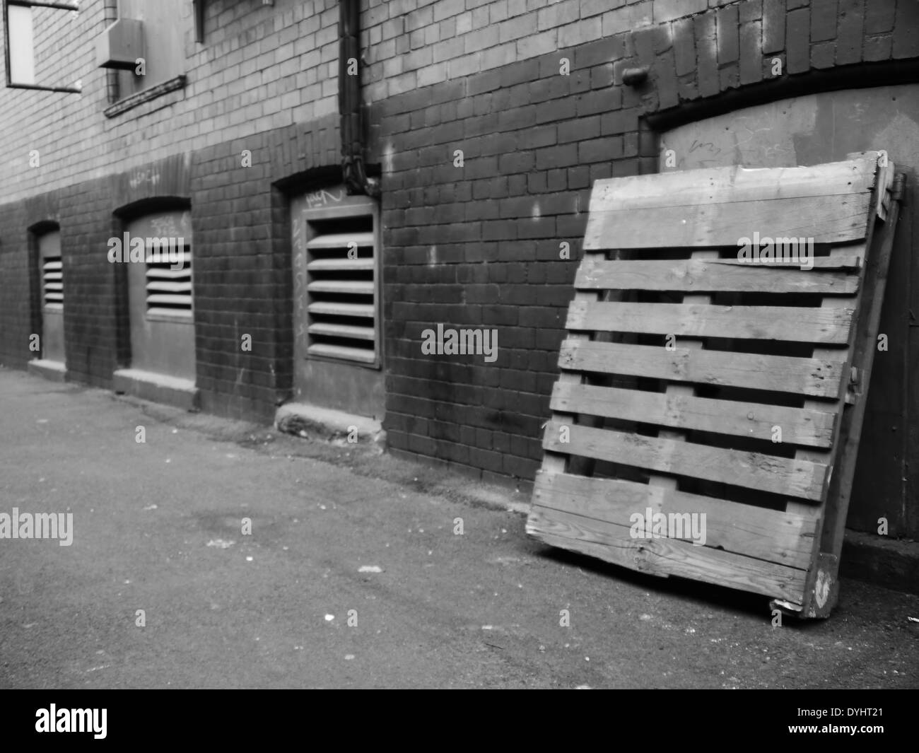 Monochrome image Urban street scene showing alley with wooden pallet
