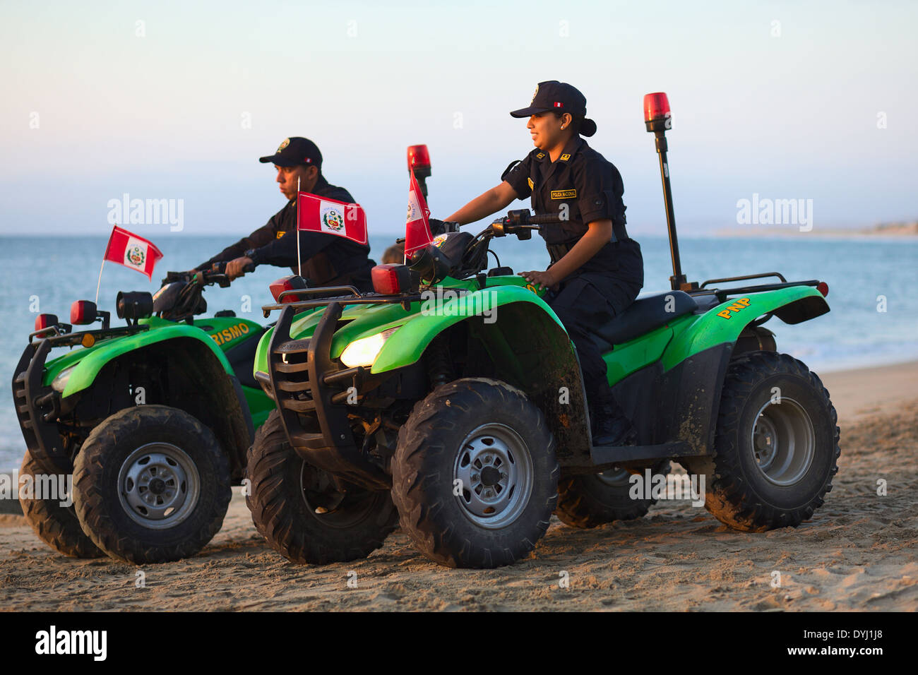 Unidentified policewoman and policeman on Honda all-terrain vehicles on the sandy beach in Mancora, Peru Stock Photo