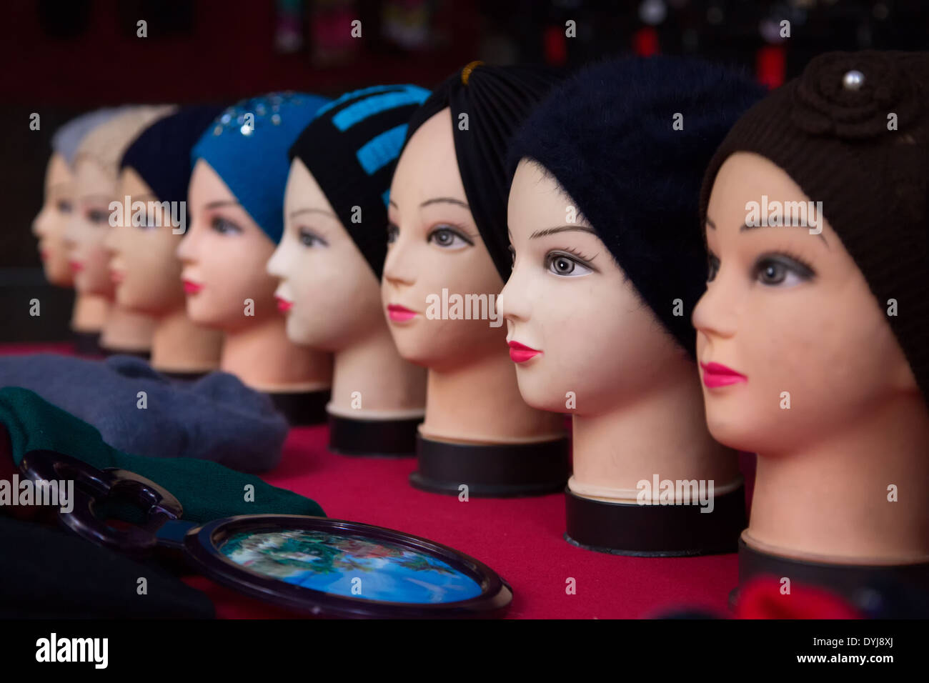 A row if mannequin heads wearing beanies in front of a mirror Stock Photo