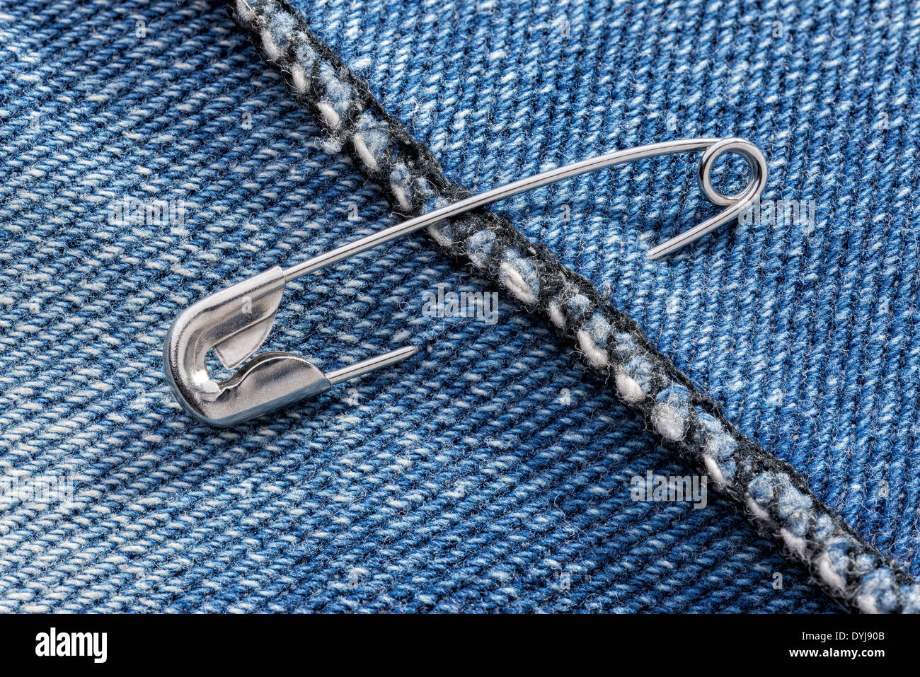 Closed safety pins on a blue jeans denim fabric Stock Photo Alamy
