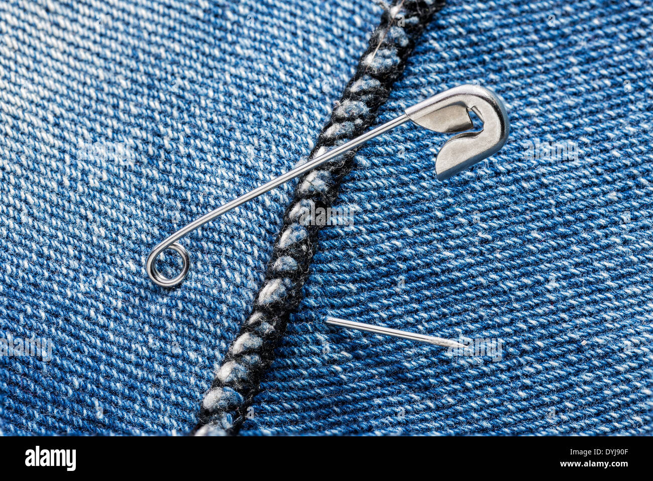 Open safety pins on a blue jeans denim fabric Stock Photo Alamy