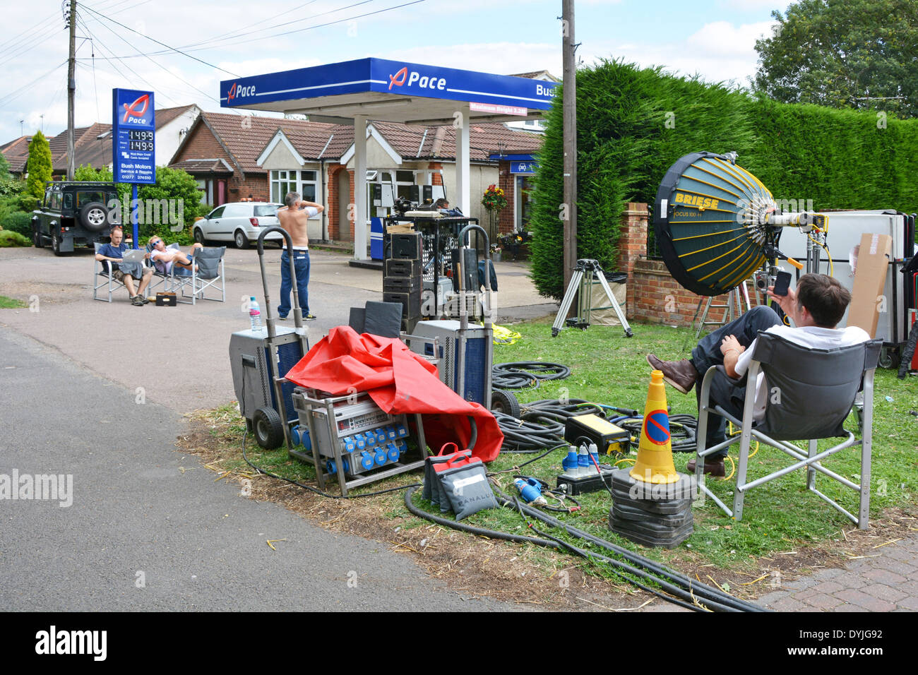 Film crew relaxing during lunch break on a hot humid summers day outside a village petrol station believed to be for TV Only Way Is Essex England UK Stock Photo