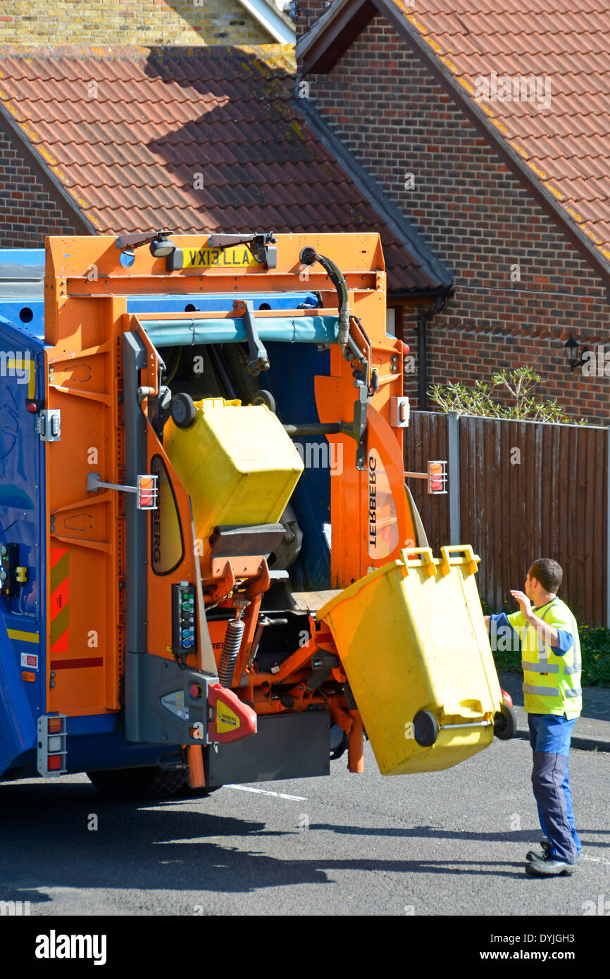 Dustman working at back of council dustcart emptying wheelie bins on hydraulic lift into lorry Stock Photo